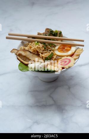 Bol à soupe de ramen avec baguettes sur table en marbre Banque D'Images