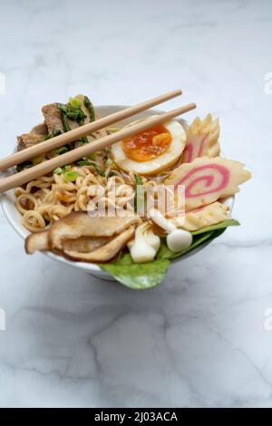 Bol à soupe de ramen avec baguettes sur table en marbre Banque D'Images