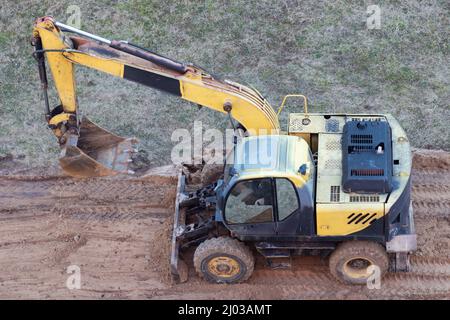 Une chargeuse sur pneus creuse le sol sur un chantier de construction pour paver une route Banque D'Images
