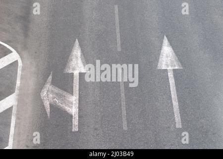 Flèches de marquage routier sur une route asphaltée pour la direction du mouvement en ligne droite ou vers la gauche Banque D'Images