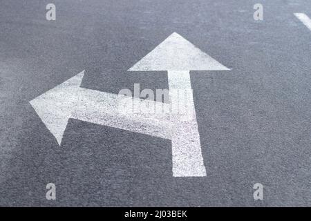 Flèches de marquage routier sur une route asphaltée pour la direction du mouvement en ligne droite ou vers la gauche Banque D'Images