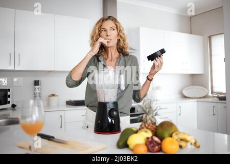 Je pense que c'est peut-être mon meilleur smoothie à ce jour. Photo d'une femme qui goûte son smoothie avant du servir. Banque D'Images