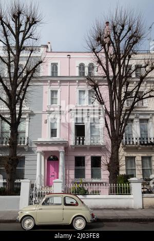 Voiture classique Fiat 500 beige d'époque garée devant une maison avec une porte rose sur une rue résidentielle de Notting Hill, à l'ouest de Londres. Banque D'Images