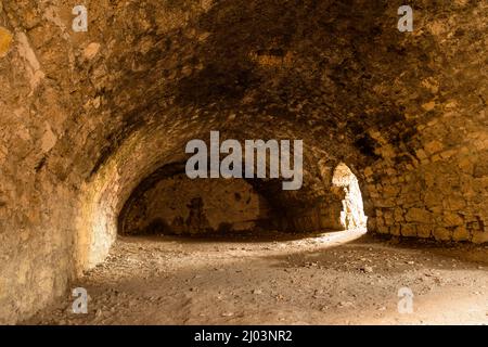 Ancienne cave voûtée du Moyen-âge, murs médiévaux en pierre orientale et sol sablonneux Banque D'Images