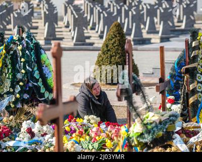 Lviv, Ukraine. 15th mars 2021. L'épouse de Rostyslav Romanchuk prend un moment pour elle-même dans sa tombe du cimetière de Lychakivske à Lviv, en Ukraine. Romanchuk a été l'un des 35 tués lors d'une frappe aérienne sur une base militaire près de la frontière polonaise. Des boureurs se sont rassemblés au cimetière de Lychakivske à Lviv pour l'enterrement de quatre soldats ukrainiens; OLEH Yaschyshyn, Sergiy Melnyk, Rostyslav Romanchuk et Kyrylo Vyshyvany, qui ont été tués par une frappe aérienne russe au Centre international pour le maintien de la paix et la sécurité, une base militaire à Yavoriv près de la frontière polonaise plus tôt dans la semaine. (Image de crédit : © Matthew Banque D'Images