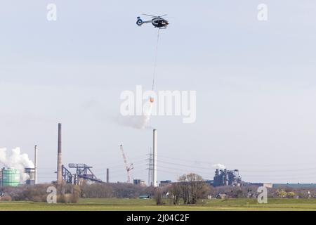 16 mars 2022, Rhénanie-du-Nord-Westphalie, Krefeld: L'eau est libérée du réservoir d'eau de lutte contre les incendies 'Bambi Bucket' par un hélicoptère Airbus H145 de la police de Rhénanie-du-Nord-Westphalie. La police de Rhénanie-du-Nord-Westphalie a été en formation avec le réservoir d'eau de lutte contre les incendies. Il les utilisera pour fournir un soutien aérien aux pompiers qui éteignent les incendies de forêt. Les « nacelles Bambi » peuvent contenir 820 litres d'eau. Photo : Marcel Kusch/dpa Banque D'Images