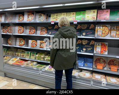 Client achetant pizza à Waitrose Rushden Northamptonshire UK Lady les clients choisissent de choisir acheter acheter marcher magasin à l'intérieur place pizza vegan Banque D'Images