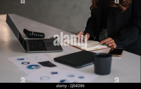 Gros plan femme d'affaires travaillant avec un ordinateur portable et prenant des notes au bureau. Concept financier d'entreprise Banque D'Images