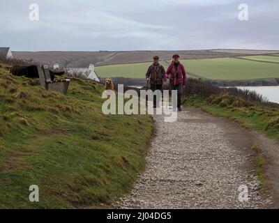 Couple d'âge mûr marchant le long du sentier de la côte sud-ouest de Daymer Bay à Polzeath, Cornwall, Royaume-Uni Banque D'Images