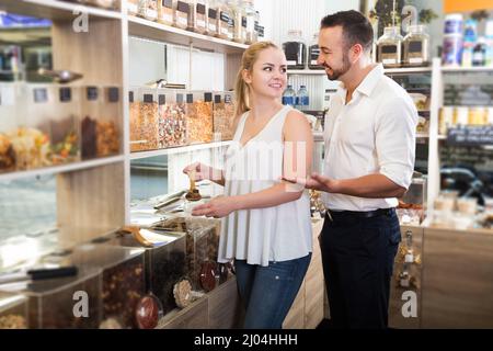 Cheerful couple prendre divers fruits confits en magasin avec produits écologiques Banque D'Images