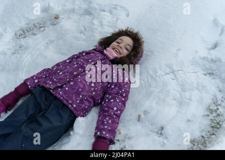 Fille jouant heureusement dans la neige dans un champ avec des oliviers Banque D'Images