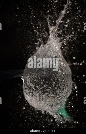 Explosion d'un ballon rempli d'eau sur fond sombre, photographie à grande vitesse, explosion rafraîchissante, avec espace de copie Banque D'Images