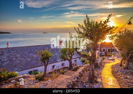 Trottoir au bord de la mer au coucher du soleil dans la ville de Primosten, une destination touristique populaire sur la côte dalmate de la mer Adriatique en Croatie, en Europe. Banque D'Images