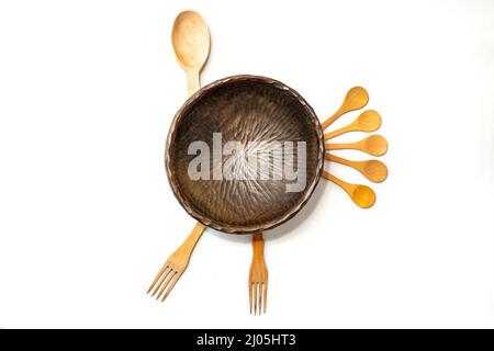 Bol en bois sculpté, cuillères à thé et fourchettes disposés comme une dinde, isolée sur fond blanc Banque D'Images