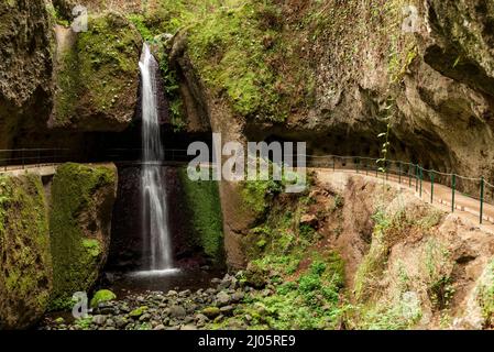 Canal d'eau Levada Nova et sentier de randonnée, passant sous une cascade dans un beau chaudron de roche dans la vallée de Ponta do sol, Madère, Portugal Banque D'Images