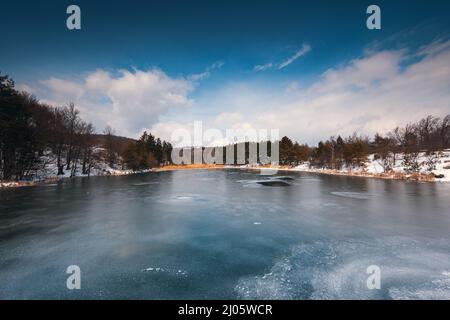 Paysage hivernal de lac de montagne gelé et forêt enneigée. Karandila, Sliven, Bulgarie Banque D'Images