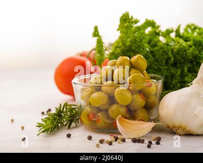 Sur fond blanc, un bol avec des olives vertes, de l'ail, du poivre noir, des tomates, des herbes. La nourriture. Alimentation saine, végétarienne, alimentation. Salade Banque D'Images