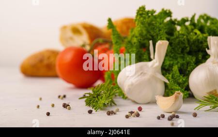 Prise de vue macro. Produits biologiques - ail, herbes, tomates, poivre noir sur fond blanc. Expérience culinaire. Nourriture végétarienne et diététique saine, vit Banque D'Images