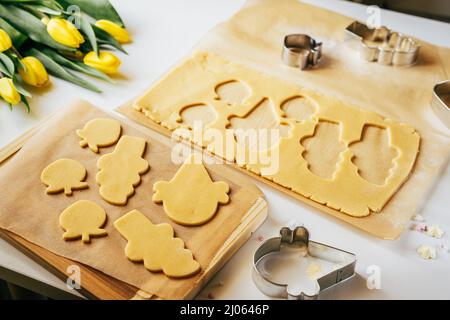 Pâte à pâtisserie coupée en petits gâteaux en forme de lapin et d'œuf. Vacances de cuisson. Vue de dessus Banque D'Images