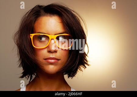 Un peu confus Photo courte d'une jeune femme attrayante portant des lunettes sur fond marron. Banque D'Images