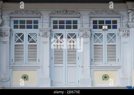 Bleu clair Straits Chinese Peranakan shophouse avec volets à persiennes en bois, motifs floraux rococo, tuiles de mosaïque paon et miroir feng shui avec Bagua Banque D'Images