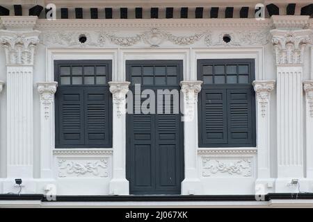 Extérieur du centre commercial Peranakan blanc Straits chinois avec persiennes en bois noir, motifs floraux rococo, colonnes en plâtre ouvragées et symboles de bonne conduite Banque D'Images