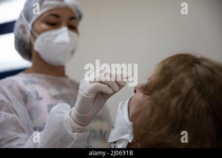 Rio de Janeiro, Brésil. 16th mars 2022. Le 16 mars 2022, un travailleur médical recueille un écouvillon auprès d'une femme pour un test COVID-19 dans un centre de santé de Rio de Janeiro, au Brésil. Le Brésil a confirmé deux cas d'infection avec la nouvelle variante Deltacron du coronavirus, qui combine les caractéristiques génétiques des variantes Delta et Omicron, a déclaré mardi le ministre brésilien de la Santé, Marcelo Queiroga. Crédit: Wang Tiancong/Xinhua/Alamy Live News Banque D'Images