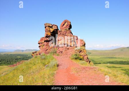 Une grande formation de pierre rouge vif au sommet d'une colline surplombant une vallée pittoresque. Coffres de montagne, Khakassia, Sibérie, Russie. Banque D'Images