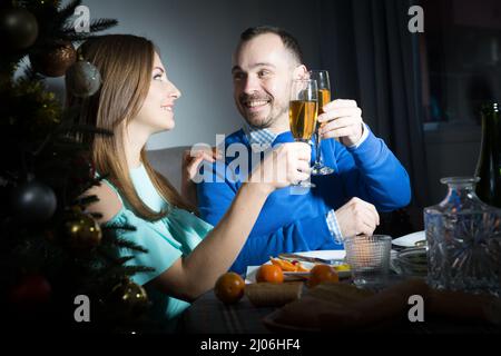 Couple souriant et aimant célébrant le nouvel an, donnant des toasts et appréciant le dîner à la maison Banque D'Images