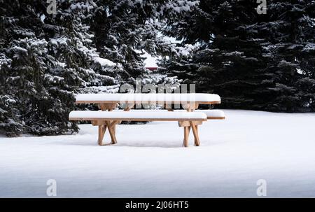 Une table de pique-nique en bois dans un parc public couvert de neige profonde à la fin de l'hiver à Calgary Alberta Canada Banque D'Images