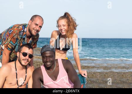 Groupe de jeunes gens regardant la caméra sur la plage Banque D'Images