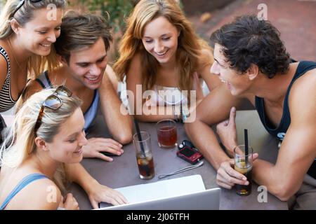 Regardez ceci. Groupe d'adolescents qui apprécient les boissons dans un restaurant en plein air avec toute leur technologie moderne. Banque D'Images