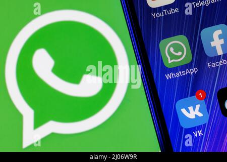 L'icône de l'application Whatsapp Messenger parmi d'autres applications sur l'écran du smartphone. En arrière-plan se trouve le logo Whatsapp. Banque D'Images