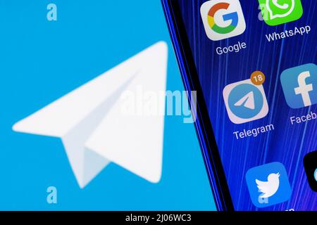 L'icône de l'application Telegram Messenger parmi d'autres applications sur l'écran du smartphone. En arrière-plan se trouve le logo Telegram. Banque D'Images