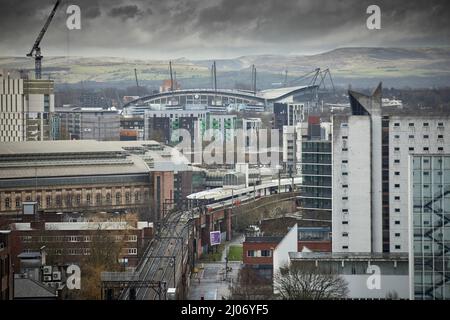 Trains à Manchester Piccadilly plates-formes 13 14, avec Manchester City FC Etihad stade sur la ligne d'horizon Banque D'Images