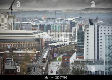 Trains à Manchester Piccadilly plates-formes 13 14, avec Manchester City FC Etihad stade sur la ligne d'horizon Banque D'Images