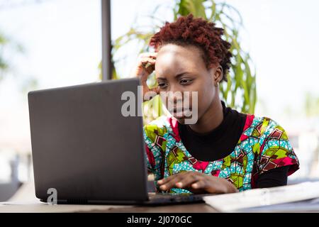 Jeune étudiant africain concentré rattraper son cours avec son ordinateur portable; préparation à l'examen, concept d'éducation académique Banque D'Images