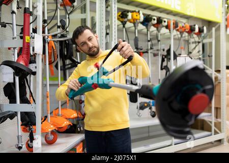 l'acheteur de sexe masculin choisit un nouveau arrosoir pour arroser les plantes Banque D'Images