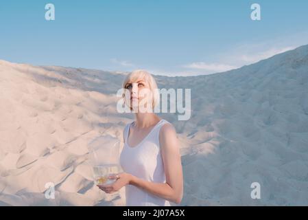 femme blonde dans le désert avec du poisson rouge dans ses mains Banque D'Images