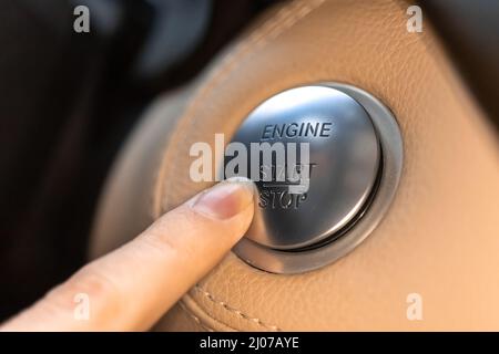 Femme appuyant sur le bouton de démarrage et d'arrêt du moteur dans une voiture sport de luxe vue rapprochée Banque D'Images