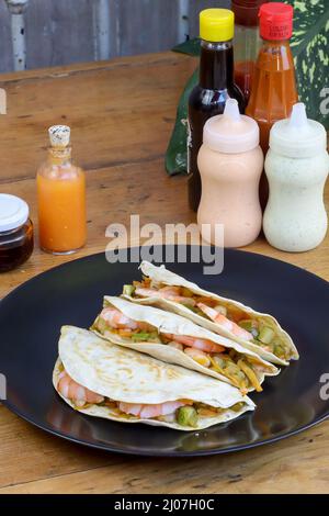 Grenaille verticale de la tortilla de farine quesadilla avec les sauces sur la table en bois Banque D'Images