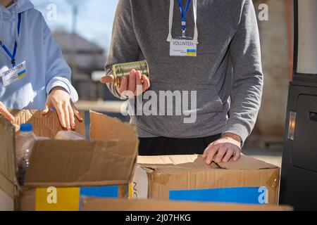 Deux volontaires se tenant près des boîtes de dons avec de la nourriture dans la banque alimentaire pour les réfugiés ukraniens. Banque D'Images