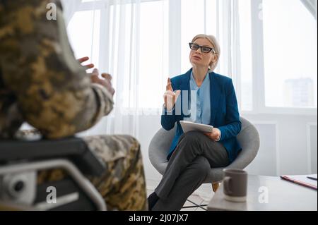 Soldat paraplégique en fauteuil roulant parlant avec un thérapeute Banque D'Images