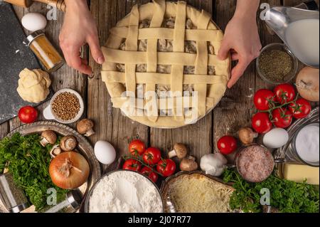 Le chef prépare une tarte à cuire sur une table en bois avec une grande variété d'ingrédients et de farine. Concept du processus de cuisson. Coulisses de la cuisine Banque D'Images