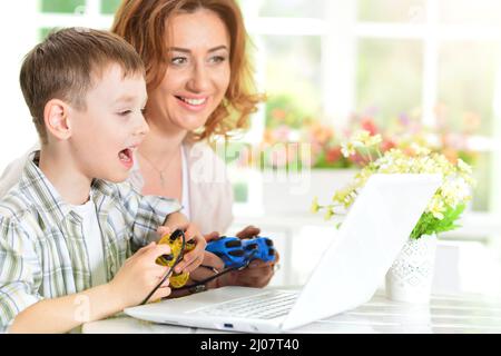 Mère et fils utilisant un ordinateur portable moderne jouant à des jeux vidéo Banque D'Images