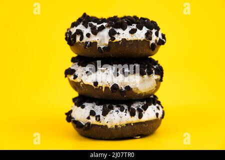 Trois beignets de chocolat sur fond jaune, trois beignets de chocolat avec saupoudrer, sur fond jaune Banque D'Images