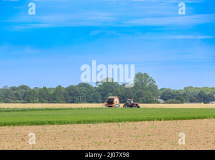 Grand tracteur agricole rouge stationné dans un champ à East Hampton, NY Banque D'Images