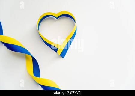 Vue de dessus des rubans bleus et jaunes en forme de symbole de coeur sur fond blanc Banque D'Images