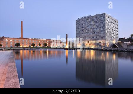 Hôtel moderne Melia Ria et centre de congrès (ancien bâtiment d'usine) se reflétant dans le canal do COJO à la tombée de la nuit, Aveiro Portugal. Banque D'Images