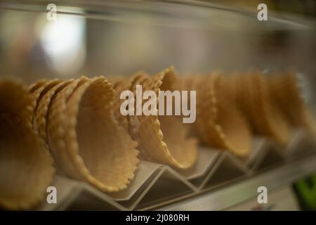 Cornets alvéolés pour la glace.Bonbons sur la fenêtre du magasin.Plats délicieux.Gaufres cuites au four. Banque D'Images